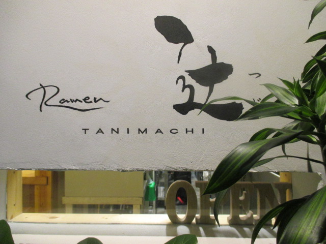 ラーメン 辻 の入口。壁に「Ramen 辻 TANIMACHI」の筆文字と、木の OPEN の札
